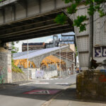 Halle couverte avec charpente en bois lamellé-collé en arrière plan. Au premier plan se situe un pont